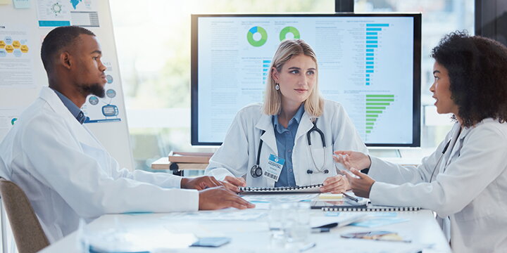 medical professionals talking in front of displays showing data visualizations