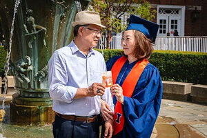 Max and Bonnie Kim holding a photo of Max's graduation
