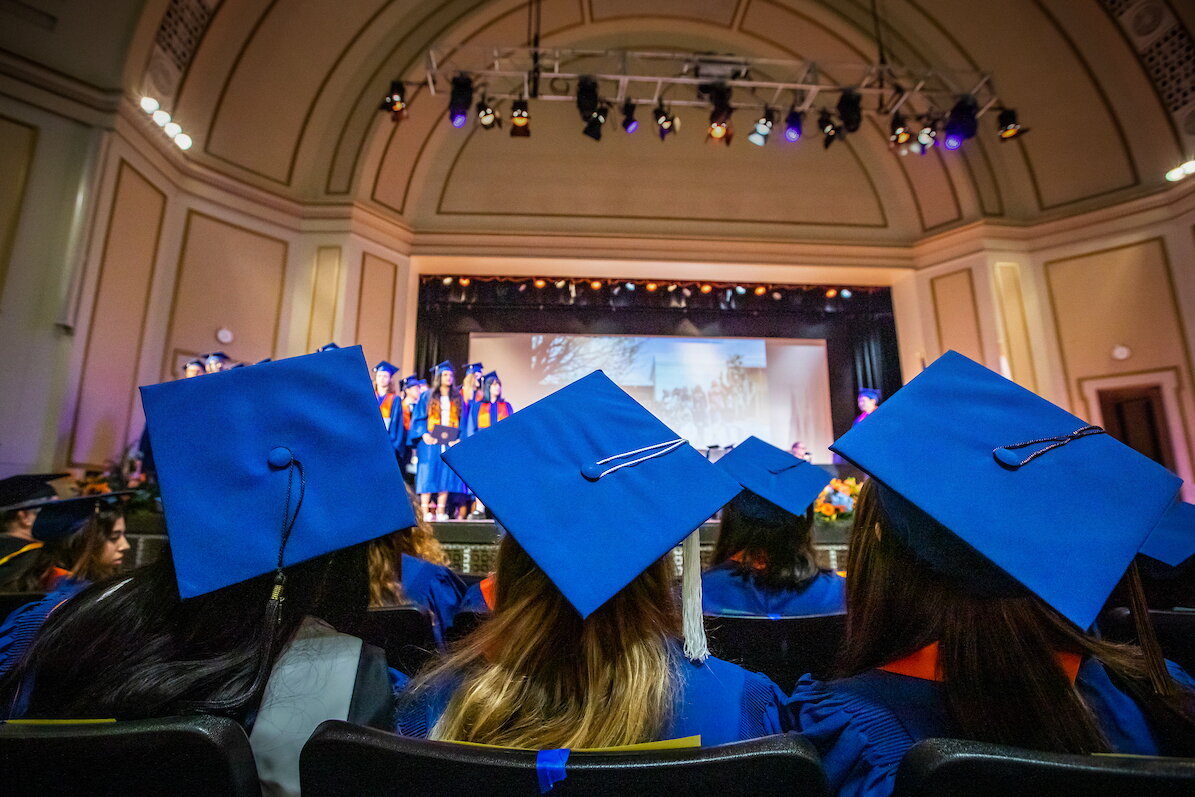 students wearing graduation caps in an auditorium