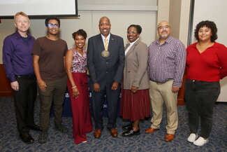 students posing next to mentor Travis Dixon during his investiture ceremony