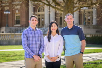 students pose with professor Brian Quick to discuss their research