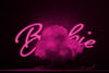 A pink-toned image of the word Barbie in a stylized font behind a pink mushroom cloud explosion