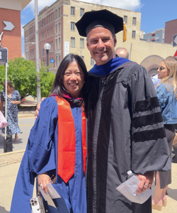 Professor Brian Quick poses with a graduate of the HCOM program in regalia